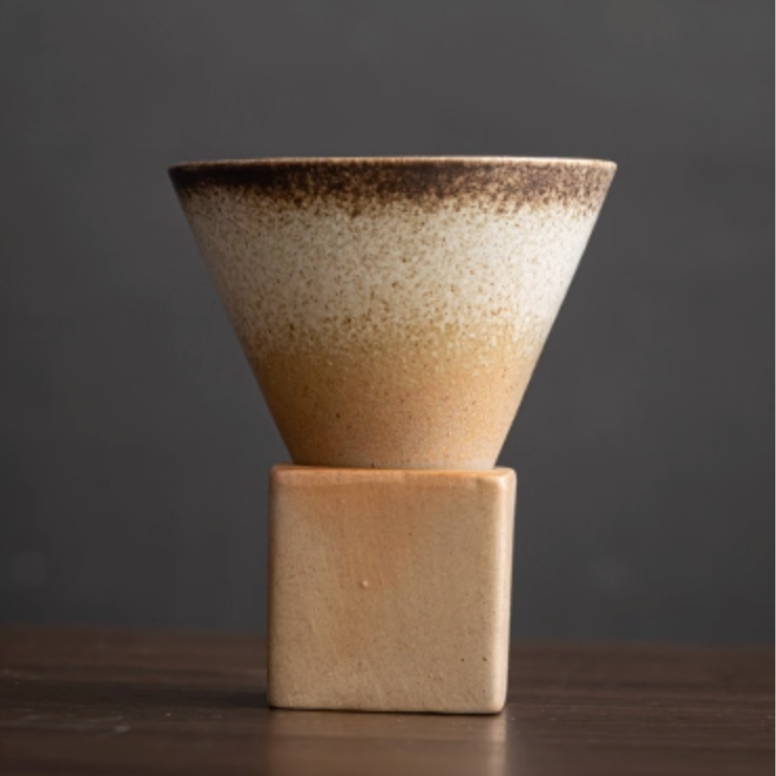 Ceramic cone-shaped coffee mug on a ceramic holder