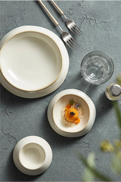 Dining setup with white ceramic plates, a glass, and silverware on a gray surface.